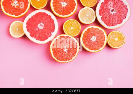 Flat lay composition with halves of different citrus fruits on pink background. Stock Photo