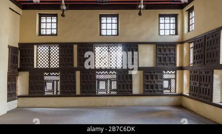 Interior wall with decorated lattice wooden windows, Mashrabiya, and sliding wooden shutters at ottoman era Amasely historic house, Rosetta City, Egypt Stock Photo