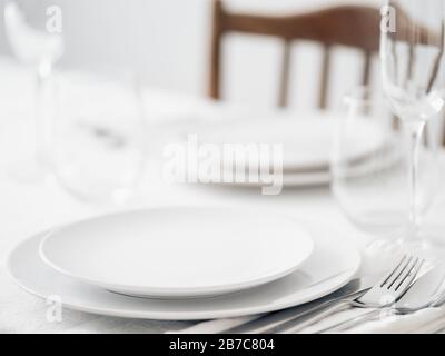 Beautiful table setting in white colors. Empty white plates. Set table for romantic dinner for two at home Stock Photo