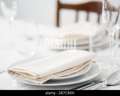 Beautiful table setting in white colors. Empty white plates. Set table for romantic dinner for two at home Stock Photo