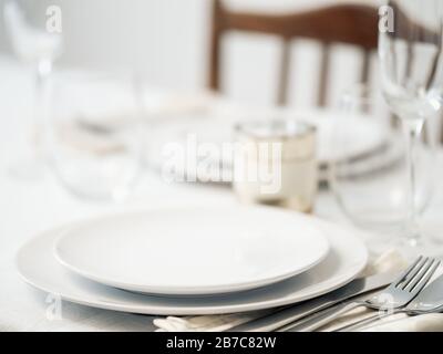 Beautiful table setting in white colors. Empty white plates. Set table for romantic dinner for two at home Stock Photo