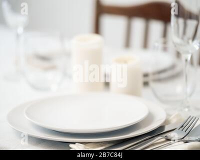 Beautiful table setting in white colors. Empty white plates. Set table for romantic dinner for two at home Stock Photo