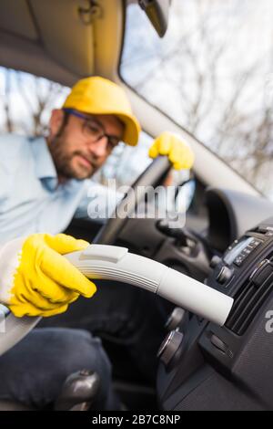 Professional handyman vacuuming car interior by using vacuum cleaner. Stock Photo