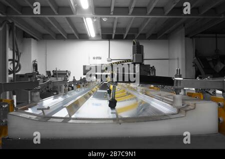 CNC machine with a metal panel clamped onto the bed in a factory workshop.  With selective colour Stock Photo