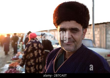 Portrait of a man wearing traditional coat and fur hat on the morning cattle market in a village near Bukhara, Uzbekistan Stock Photo