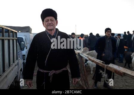 Portrait of a man wearing traditional coat and fur hat on the morning cattle market in a village near Bukhara, Uzbekistan Stock Photo