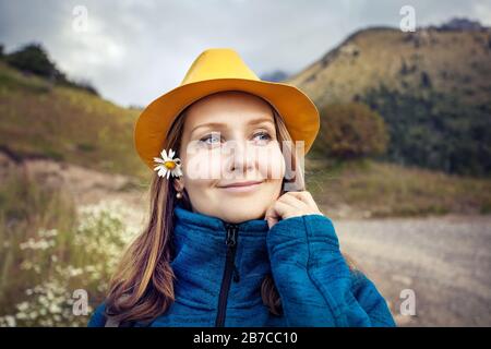 Young and happy woman tourist in yellow hat portrait on mountains in Kazakhstan Stock Photo