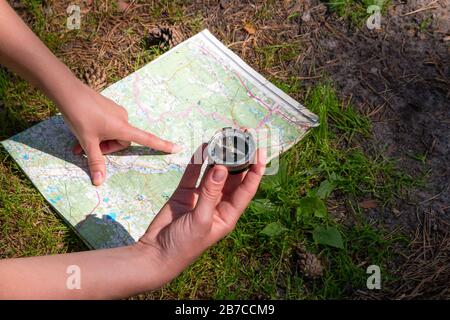 woman traveler checks with the route using a map and compass Stock Photo