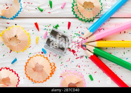 colored pencils and pencil sharpener on a white wooden background Stock Photo