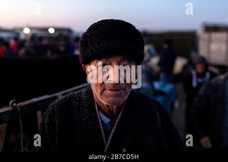 Portrait of a man wearing traditional coat and fur hat on the morning cattle market in a village near Bukhara, Uzbekistan Stock Photo