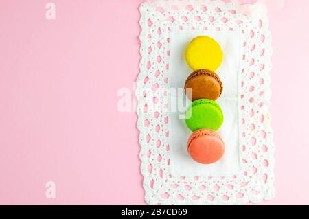 Several multicolored macaroons pastel colors on a white napkin on pink background Stock Photo