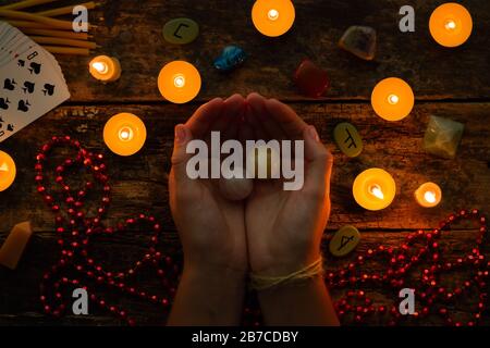 fortuneteller holds crystal balls for divination against a background of candles and runes Stock Photo