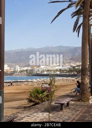 Playa de las Americas in Tenerife, Canary islands Spain. Beach, sea, promenade with benches and mount Teide in the hazy blue distance Stock Photo
