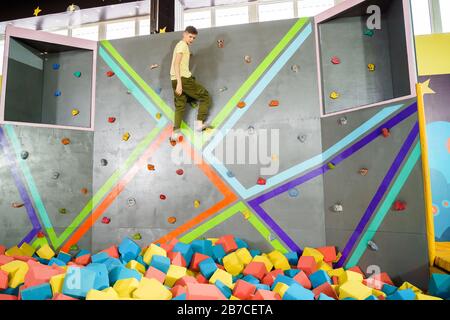 Teenage boy on climbing wall in trampoline center. Adventure and extreme for teenager concept Stock Photo