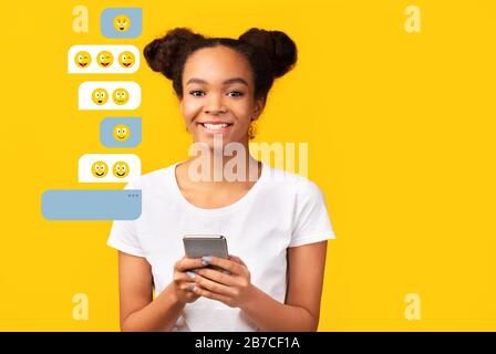 Online chat. African American woman using mobile phone for friendly talk on orange background, space for text Stock Photo