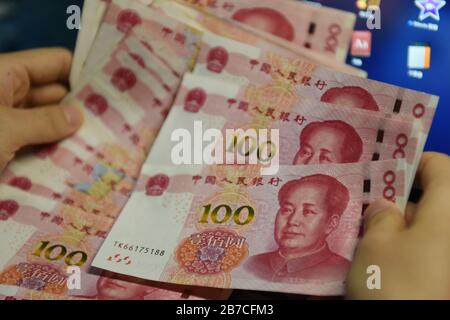 In this photo illustration a man holds 100 RMB notes. Stock Photo