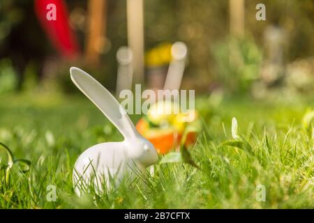 White Easter bunny figure and dyed eggs on the green grass  on a sunny day Stock Photo