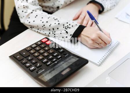 The girl is engaged in accounting. Woman's hand writes in a notebook home expenses and income. The concept of the distribution of cash, compliance with the family budget. Stock Photo