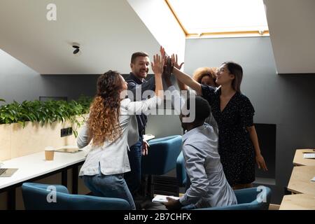 Diverse employees team giving high five, celebrating successful deal ...