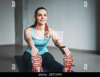 Attractive fit young woman sport wear fitness girl model doing stretching at the loft studio workout class Stock Photo