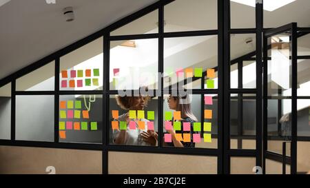 Diverse colleagues discussing project plan on sticky papers in office Stock Photo