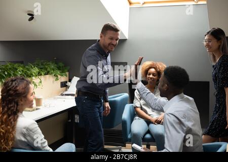 Smiling team leader giving high five to African American employee Stock Photo