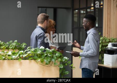 Smiling diverse employees talking, chatting in office during break Stock Photo