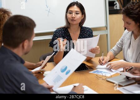 Confident Asian businesswoman discussing documents at meeting in boardroom Stock Photo