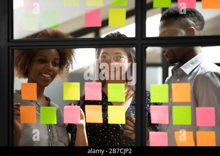 Happy smiling diverse colleagues working with sticky papers together Stock Photo