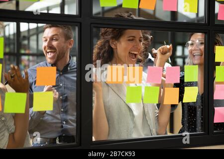 Happy leader with diverse employees team celebrating success at meeting Stock Photo
