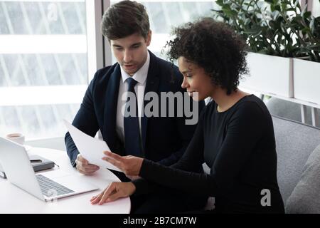 Divers colleagues sit at desk in office brainstorm working on computer together Stock Photo