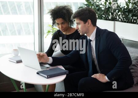 Multiracial employees work at laptop discussing project Stock Photo
