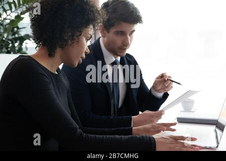 Multiracial colleagues brainstorm using laptop in office Stock Photo