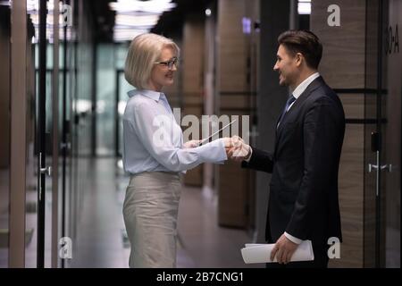 Smiling businesspeople shake hands greeting in office Stock Photo