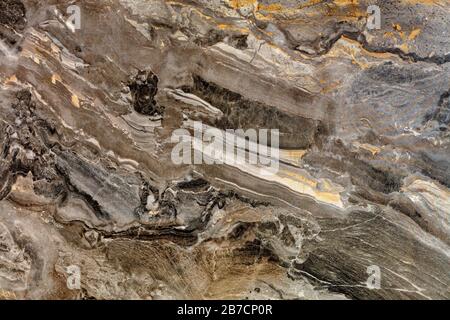 Unusual texture of brown marble with beige and black spots, stains and stripes. Polished surface. Stock Photo