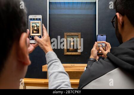 Two tourists using their smartphones to take pictures of the Mona Lisa painting by artist Leonardo da Vinci, Louvre Museum, Paris, France, Europe Stock Photo