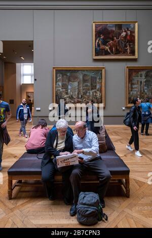 Elderly tourists looking at a map of the Louvre Museum in Paris, France, Europe Stock Photo