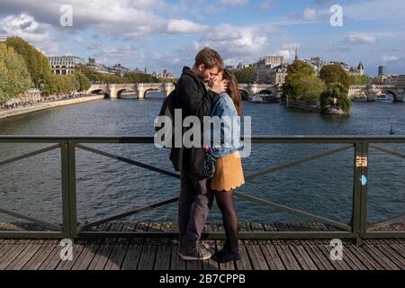 Young couple in love kissing passionately on the Pont des Arts lovers lock bridge in Paris, France, Europe Stock Photo