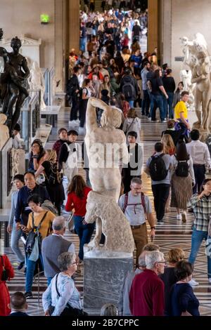 Rear view of thDying Slave marble sculpture by Italian Renaissance artist Michelangelo on a crowded room at the Louvre Museum in Paris, France, Europe