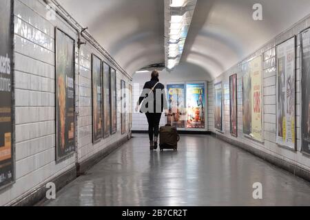 Woman with rolling suitcase walking away in the parisian metro in Paris, France, Europe Stock Photo