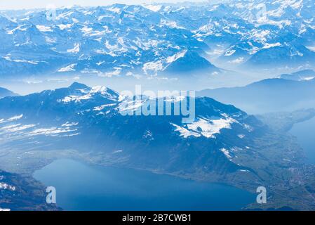 Unique alpine aerial panorama. Blue Planet Earth high altitude aerial view of Swiss Alps lakes, seen from an airplane cabin window flying over Zurich Stock Photo