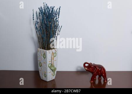 Vase with preserved lavender and Indian elephant symbol of prosperity, wealth and stability on a wooden brown chest. Copyspace.