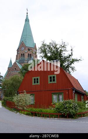 Traditional wooden house painted in traditional red against the Sofia Church in the background located in Stockholm, Sweden Stock Photo