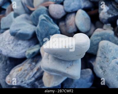 Stack of triangular stones.Group of white and colorful Stones.Pebble tower on the stones seaside.Stones pyramid on pebble beach symbolizing stability, Stock Photo