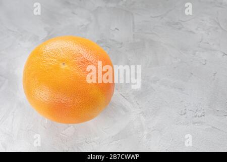 One red ripe grapefruit on gray background. CLose up, copy space Stock Photo