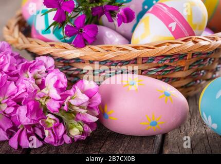 Closeup of colorful flowers and easter eggs on an old wooden surface Stock Photo