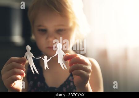 little girl with paper family in hands. concept of divorce, custody and child abuse Stock Photo