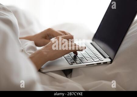 Young woman using computer in bed after waking up. Stock Photo