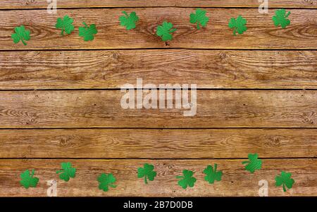 Paper clover leaves on the old wooden background. Lucky shamrock, St.Patrick's day holiday symbol. Space for text, top view. Stock Photo