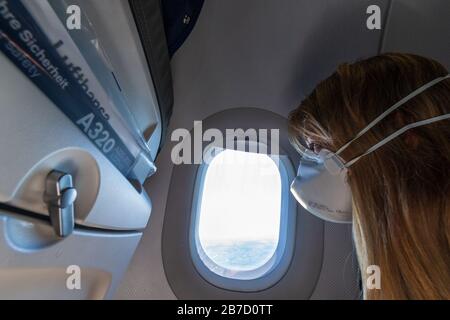 Europe - March 15th 2020: Woman on a plane with face mask for protection against the sars-cov-2 virus Stock Photo